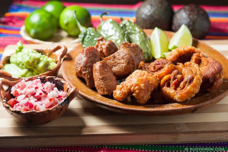 plato con chicharrones, carnitas, chile, limones, aguacate y chojin guatemalteco