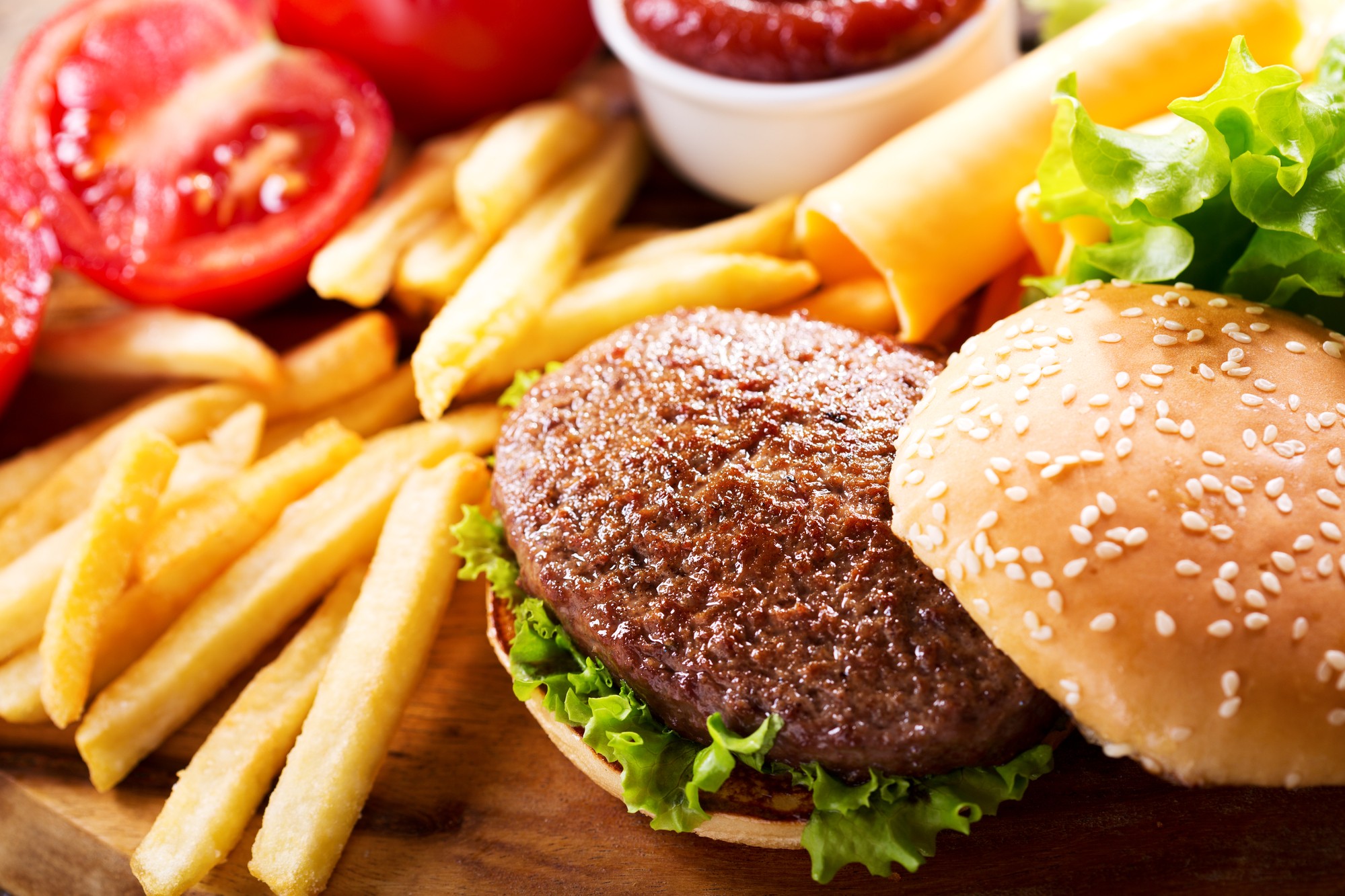 Deliciosa hamburguesa con papas fritas, lechuga y tomate, con salsa en el fondo