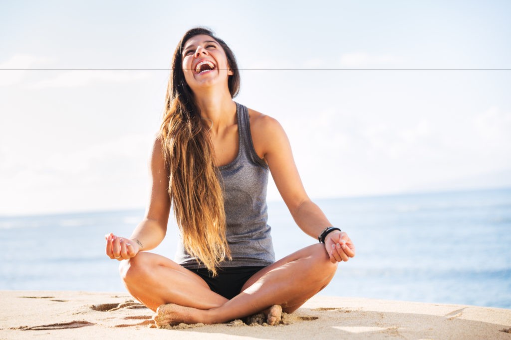 mujer en posición de meditación riendo y sin estrés